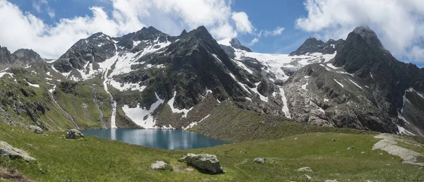 Blick auf den türkisblauen Bergsee Grunausee in alpiner Landschaft mit grünen Wiesen und schneebedeckten Berggipfeln. Tirol, Stubaier Alpen, Österreich, Sommersonniger Tag — Stockfoto