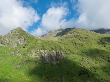 view on green mountain peaks with water streams from melting snow, summer sunny day, blue sky white clouds. Tirol, Austrian Alps