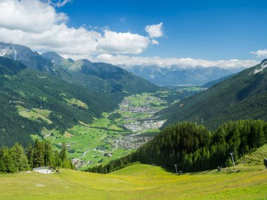 View over green Stubai valley and Neustift im Stubaital village from Elferhutte with moutain peaks and kites. Tirol Alps, Austria, Summer blue sky, white clouds