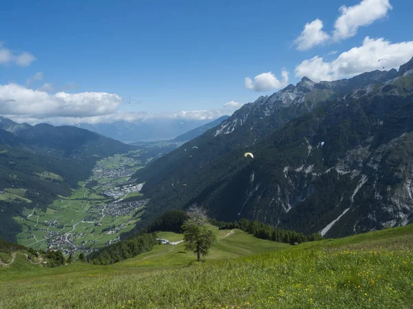 View over green Stubai valley and Neustift im Stubaital village from Elferhutte with moutain peaks and kites. Tirol Alps, Austria, Summer blue sky, white clouds