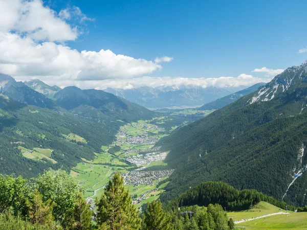 View over green Stubai valley and Neustift im Stubaital village from Elferhutte with moutain peaks and kites. Tirol Alps, Austria, Summer blue sky, white clouds