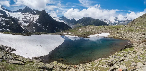 Πανοραμική άποψη της παγετώδους λίμνης με πηγές από λιώσιμο παγετώνα με αιχμηρές χιονισμένες βουνοκορφές που αντανακλούν στην επιφάνεια του νερού. Tyrol, Stubai Alps, Αυστρία, ηλιόλουστη μέρα του καλοκαιριού — Φωτογραφία Αρχείου