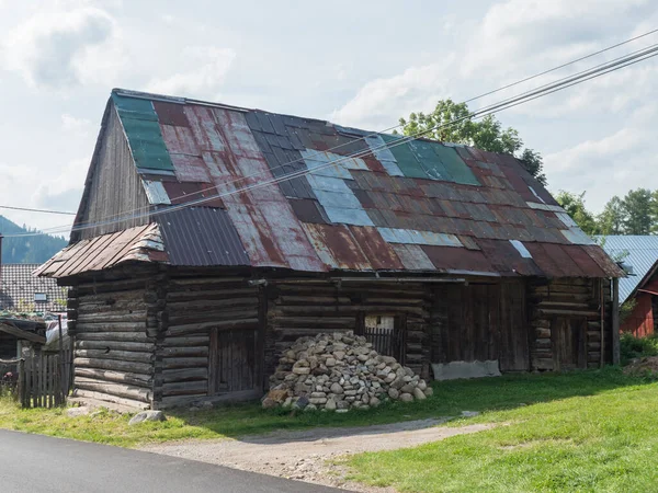 Liptovska luzna, Low Tatras, Slovakia, August 30, 2020: Old shabby log cabin cottage, timbered rural house with rusty sheet metal roof in village Liptovska luzna, summer sunny day — Stock Photo, Image