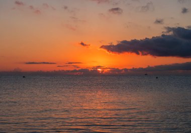 Kırmızı turuncu güneşle gün doğumu koyu bulutlarla birlikte plajdan yükseliyor Spiaggia di Santa Maria Navarrese, Sardinya, İtalya