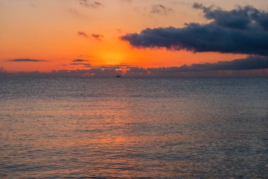 Kırmızı turuncu güneşle gün doğumu koyu bulutlarla birlikte plajdan yükseliyor Spiaggia di Santa Maria Navarrese, Sardinya, İtalya