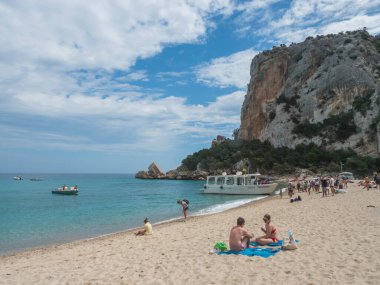 Cala Gonone, Sardinya, İtalya, 9 Eylül 2020: güneşlenen insanlar ve turizm teknesi ile Cala Luna plajı. Kireç taşlı beyaz kumsal, turkuaz mavi su. Ünlü turistik seyahat.