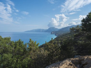 Orosei Körfezi üzerinde kireçtaşı kayalıkları, yeşil çalılar, beyaz plaj ve turkuaz mavi su manzarası. İtalya 'nın Sardunya adasında ünlü turistik tatil beldesi.