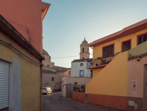 Calle en el casco antiguo de Tortoli con torre de la iglesia y casas de color rosa amarillo. Cerdeña, Italia, tarde de verano — Foto de Stock