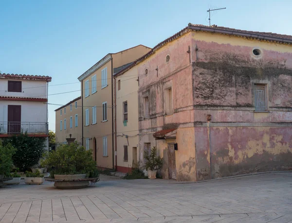 Calle en el casco antiguo de Tortoli con casas de color rosa amarillo y plantas verdes. Cerdeña, Italia, tarde de verano — Foto de Stock