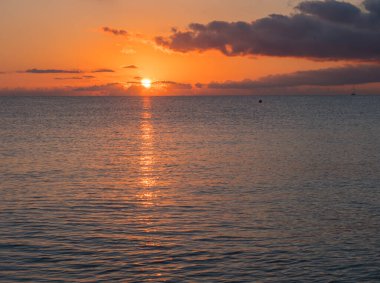 Kırmızı turuncu güneşle gün doğumu koyu bulutlarla birlikte plajdan yükseliyor Spiaggia di Santa Maria Navarrese, Sardinya, İtalya