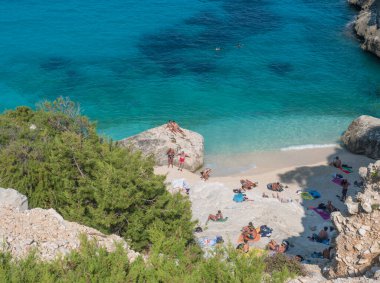Orosei Körfezi, Sardunya, İtalya, 8 Eylül 2020: Cala Goloritze plajında banyo yapan turistlerin manzarası. Kireçtaşı kayası ve turkuaz mavi suyu olan beyaz çakıl taşları plajı. Ünlü seyahat.