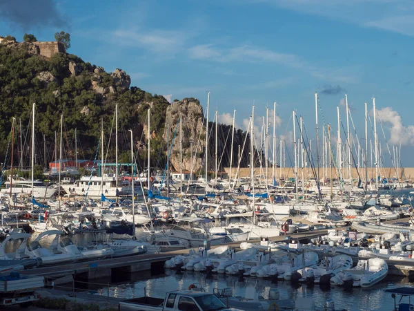 Santa Maria Navarrese, Sardinien, Italien, 12. September 2020: Blick auf den Yachthafen von Santa Maria Navarrese mit Segelschiffen, Fischerbooten und einem grünen Hügel mit Felsen. Sommer, goldene Stunde Licht — Stockfoto
