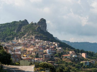 Cityscape of old pictoresque village Ulassai with limestone climbing rock and green vegetation and mountains at countryside of Sardinia island. Summer sunny day. Province Nuoro, Sardinia, Italy clipart