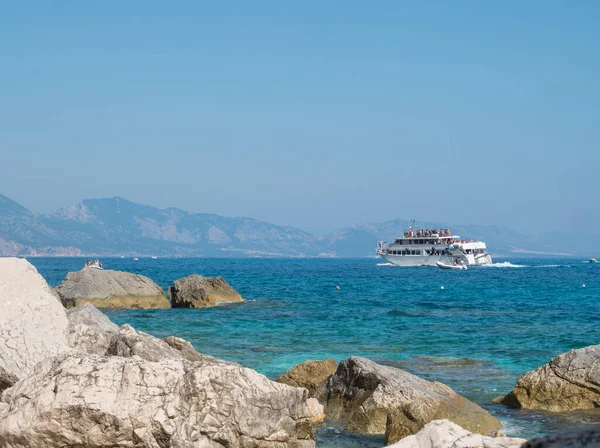 Cala Goloritze, Sardinien, Italien, 8. September 2020: Ein Blick auf das touristische Kreuzfahrtschiff am türkisblauen Wasser des Golfs von Orosei von der felsigen Küste aus — Stockfoto