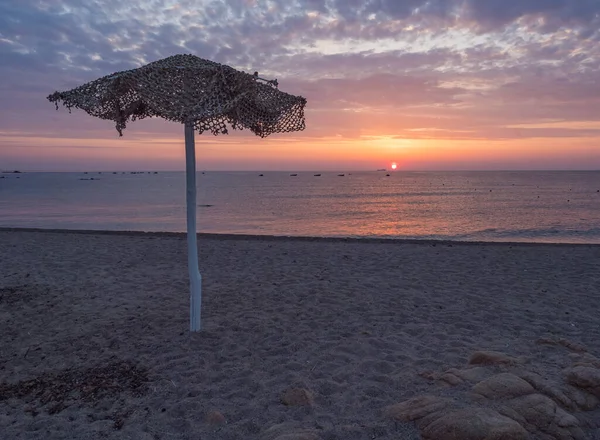 Színes napfelkelte az üres strandon Spiaggia di Santa Maria Navarrese fa napernyővel, vörös nap emelkedik fel a tengerből, és rózsaszín kék és narancssárga felhők. Szardínia, Olaszország — Stock Fotó