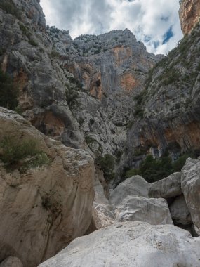 Gola Su Gorropu geçidi, kireçtaşı kaya duvarları, yeşil çalılar ve ağaçlarla kaplı. Supramonte Dağları, Nuoro, Sardinya, İtalya 'da ünlü turist yürüyüş merkezleri. Yaz.