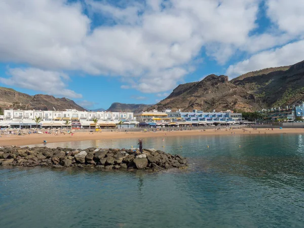 Puerto de Mogan, Gran Canaria, Canarische Eilanden, Spanje 18 december 2020: Zicht op het openbare strand met goudkleurig zand en appartementen in het populaire vakantiedorp Puerto de Mogan op zonnige dag — Stockfoto