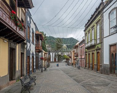 Teror, Gran Canaria, Kanarya Adaları, İspanya 21 Aralık 2020: Renkli cepheli tarihi Teror kasabasının ana caddesi, geleneksel ahşap balkon ve kilise Bazilikası de Nuestra Senora del