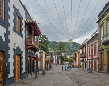 Teror, Gran Canaria, Kanarya Adaları, İspanya 21 Aralık 2020: Renkli cepheli tarihi Teror kasabasının ana caddesi, geleneksel ahşap balkon ve kilise Bazilikası de Nuestra Senora del