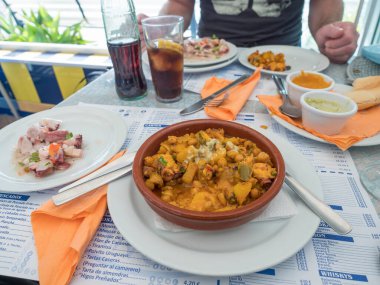 Puerto de las Nieves, Gran Canaria, Kanarya Adaları, İspanya 24 Aralık 2020: Ropa Vieja güveci, nohut, ahtapot salatası ve soslu restoran masası. Kanarya Adaları 'ndan tipik yemek