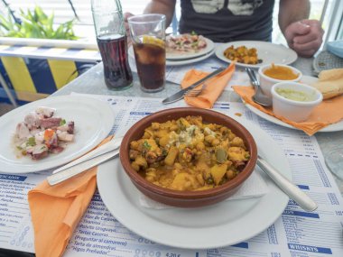 Puerto de las Nieves, Gran Canaria, Kanarya Adaları, İspanya 24 Aralık 2020: Ropa Vieja güveci, nohut, ahtapot salatası ve soslu restoran masası. Kanarya Adaları 'ndan tipik yemek