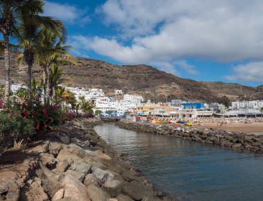 Puerto de Mogan, Gran Canaria, Kanarya Adaları, İspanya 18 Aralık 2020: Güneşli bir günde popüler tatil köyü Puerto de Mogan 'da altın kum ve apartmanlı halk plajı manzarası