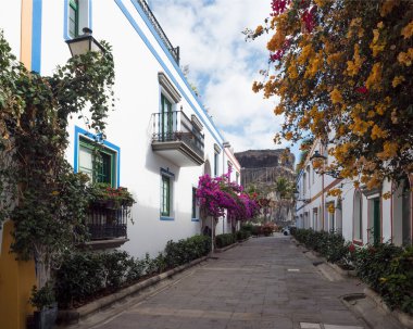 Puerto de Mogan, Gran Canaria, Kanarya Adaları, İspanya 18 Aralık 2020: Küçük balıkçı köyü limanı Puerto de Mogan 'ın yaya yolundaki geleneksel renkli evler.