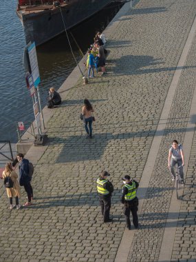 Prag, Çek Cumhuriyeti, 26 Mart 2021: Polis memurları güneşli baharda Vltava nehrinin dolgusu altında insanları kontrol ediyor. Üst görünüm.
