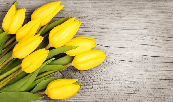Gelbe Tulpen auf einem hölzernen Hintergrund — Stockfoto