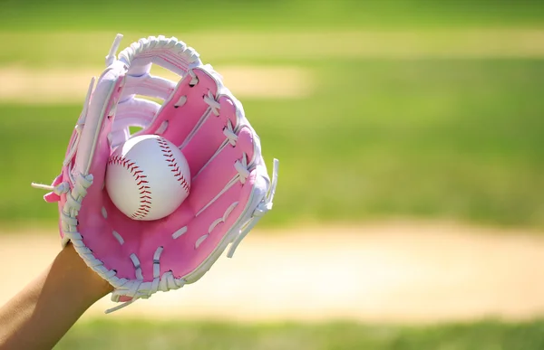 Hand van honkbalspeler met roze handschoen en bal over veld — Stockfoto