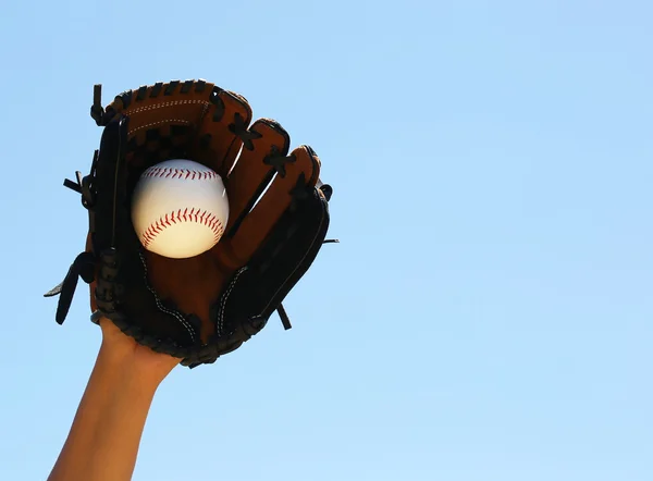 Mão do jogador de beisebol com luva e bola sobre céu azul — Fotografia de Stock