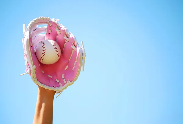 Hand eines Baseballspielers mit rosa Handschuh und Ball über blauem Himmel — Stockfoto