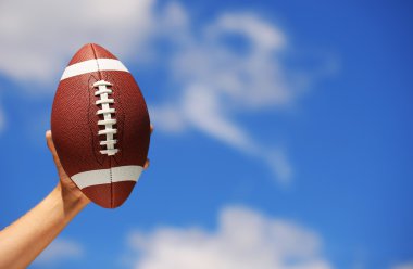 Mavi gökyüzü üzerinde elinde Amerikan futbolu