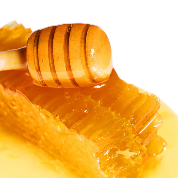 Favo de mel com mergulhador de mel de madeira, isolado em branco. Macro — Fotografia de Stock