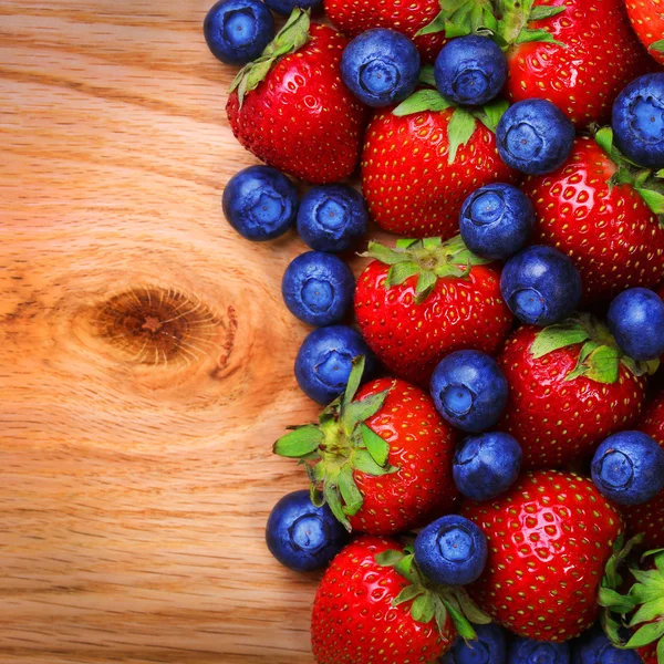 Bayas. Fresas y arándanos sobre fondo de madera — Foto de Stock