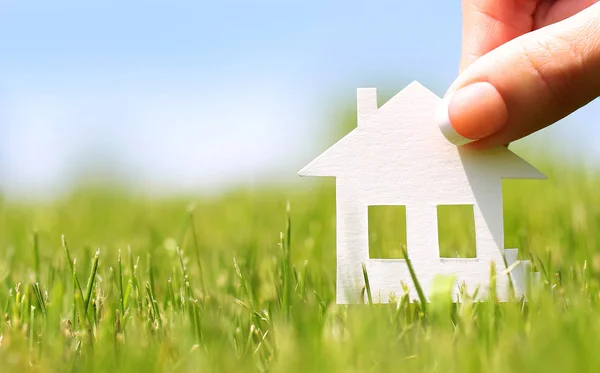 Paper house in green grass over blue sky. Mortgage concept — Stock Photo, Image
