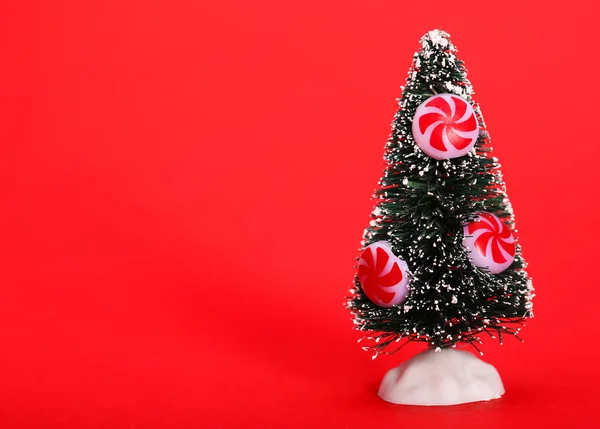 Kerstboom met pepermunt snoep op rode achtergrond — Stockfoto