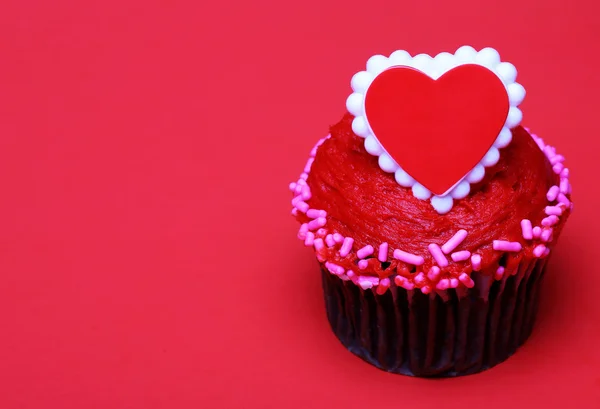 Magdalena de chocolate con corazón rojo en la parte superior, sobre fondo rojo — Foto de Stock