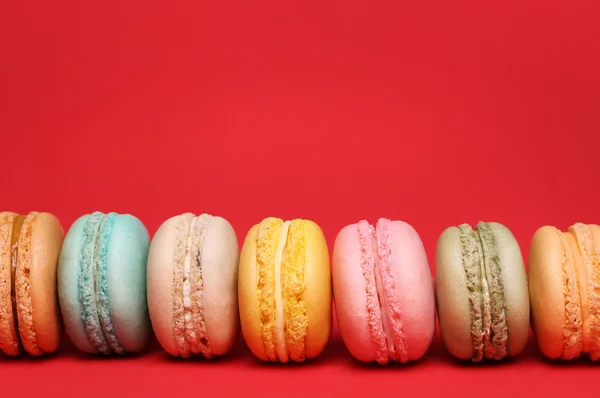 Színes francia Macarons felett piros háttér — Stock Fotó