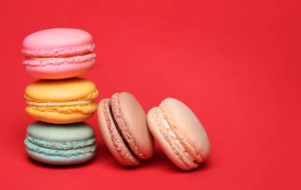 Barevná francouzská Macarons na červeném pozadí — Stock fotografie