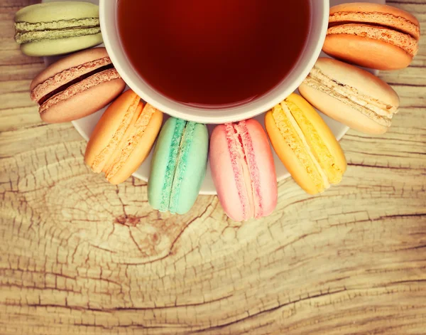 Färgglada franska Macarons med Cup of Tea på trä bakgrund. Topp — Stockfoto