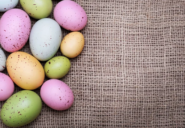 Barevné velikonoční vejce na pytlovina pozadí — Stock fotografie