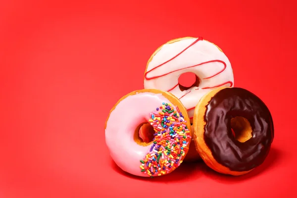 Sweet donuts on red background — Stock Photo, Image