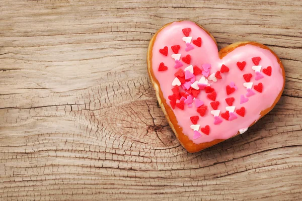 Heart shaped donut on wooden background — Stock Photo, Image