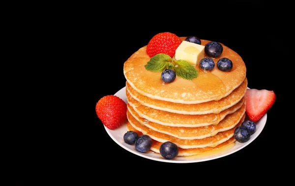 Pannkakor med jordgubb och blåbär över svart bakgrund — Stockfoto