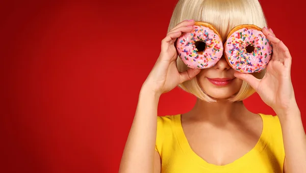 Blonde Frau mit bunten Donuts auf rotem Hintergrund — Stockfoto