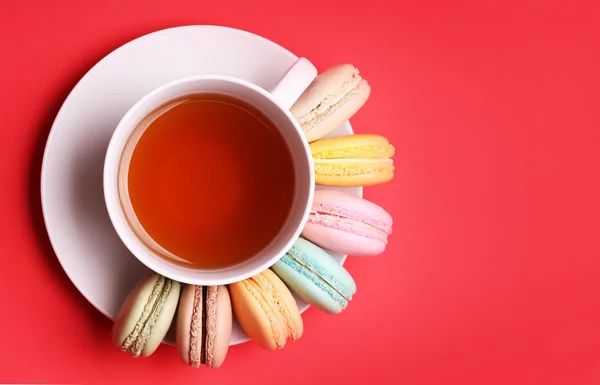 Kolorowy Macaroons francuski z Cup of Tea na czerwonym tle — Zdjęcie stockowe