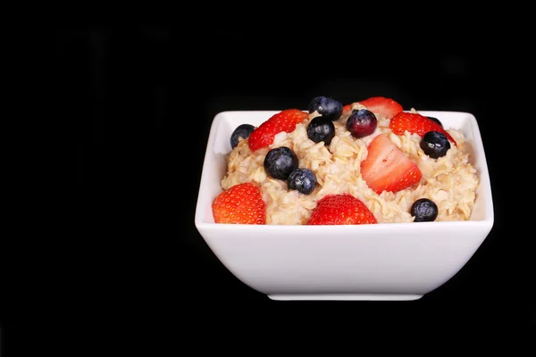 Haferflocken mit Beeren über Schwarz — Stockfoto