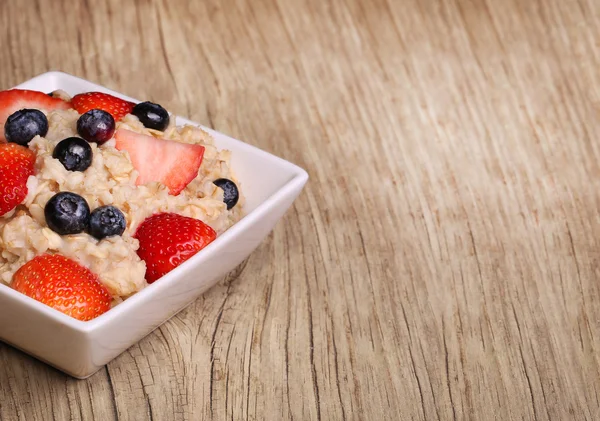 Haferflocken mit Beeren auf Holzgrund — Stockfoto