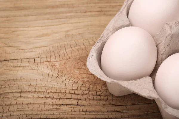 Huevos blancos en la caja sobre fondo de madera — Foto de Stock